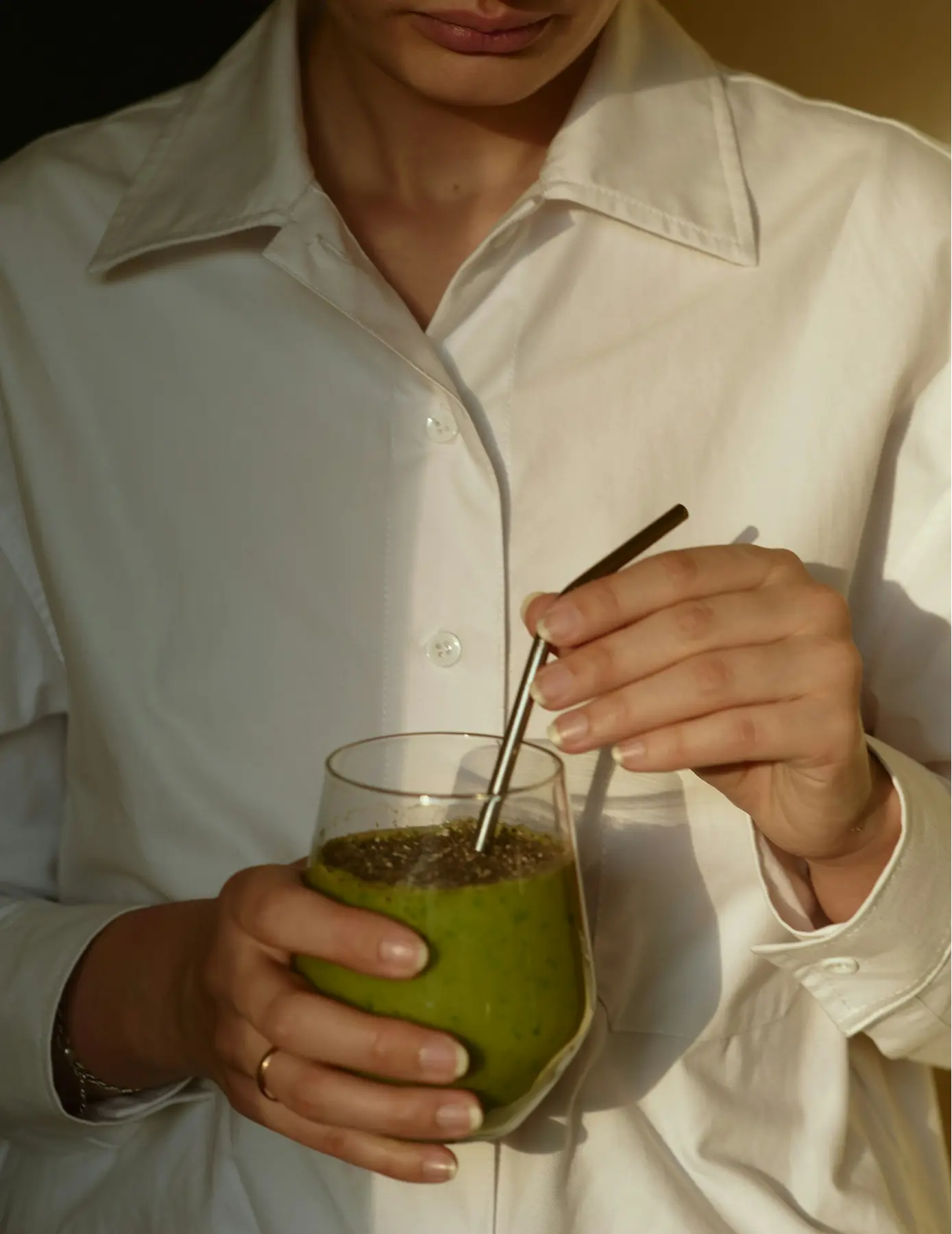 Woman in a white shirt holding a matcha drink
